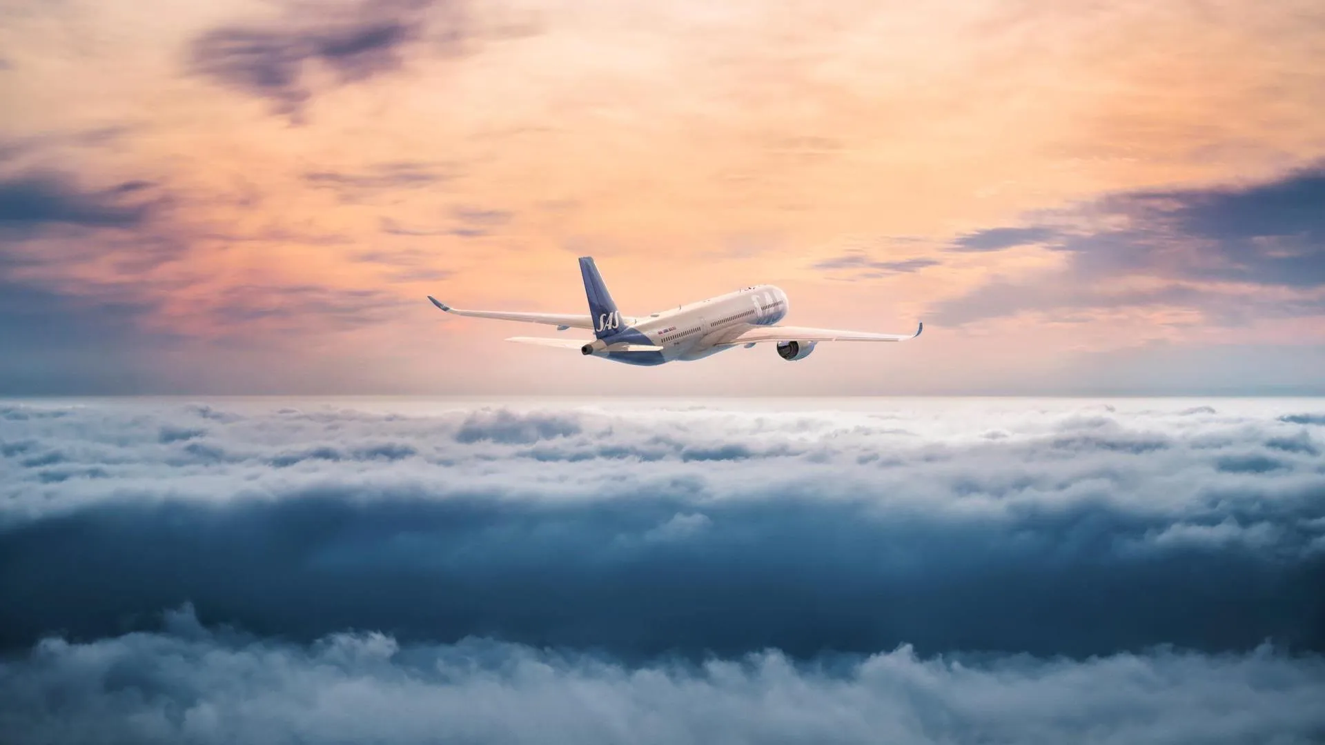 SAS-flygplan över molnen i solnedgång